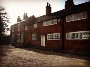 un vecchio edificio in mattoni rossi con una porta bianca di The Falcon Inn a Long Whatton