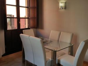 uma sala de jantar com uma mesa de vidro e cadeiras brancas em Apartamento Capitania em Granada