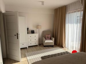 a bedroom with a bed and a chair and a mirror at Apartament NADJEZIORNA EŁK in Ełk