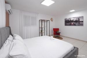 a bedroom with a white bed and a red chair at וילה ויליז'ן in H̱azon +38 photos