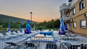 a pool with chairs and blue umbrellas next to a building at Apartments Ljiljanic in Budva