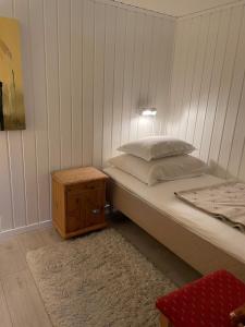a bedroom with a bed and a wooden night stand at Sokkelleilighet med 3 soverom in Molde
