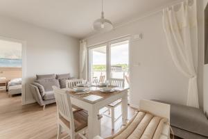 a white living room with a table and a couch at Sunset Resort VI, Nadmorska 98A in Grzybowo