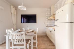 a kitchen with a table and chairs and a white refrigerator at Sunset Resort VI, Nadmorska 98A in Grzybowo