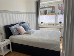 a bedroom with a bed with pillows and a window at Ferienwohnung Norddeich in Norden