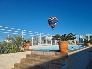 a hot air balloon flying over a swimming pool at Hotel Jardim do Mar in Torres