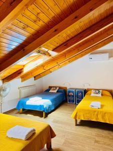 Dos camas en una habitación con techos de madera. en Albergue Só Por Hoje , Albergue para Peregrinos del Caminho de Santiago, en Astorga