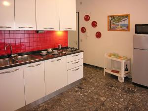 una cucina con armadi bianchi e piastrelle rosse sul muro di Appartamenti Nettuno Pineda a Bibione