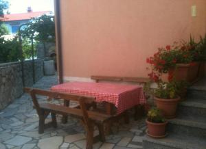 ein Tisch und eine Bank auf einer Terrasse mit Pflanzen in der Unterkunft Apartment Sofia in Cres