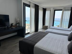 a hotel room with two beds and a television at Palladium Beach Resort- Luxury Leading Hotels, Private Beach Included in Dhërmi
