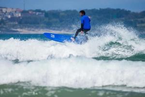 Ein Mann reitet auf einem Surfbrett eine Welle im Meer in der Unterkunft SURFbase Loredo in Loredo