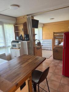 a kitchen with a wooden table and a room with a bed at Studio station Puy-Saint-Vincent in Puy-Saint-Vincent
