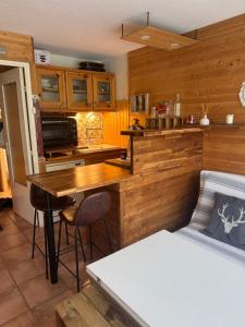 a kitchen with wooden cabinets and a table and a bed at Studio station Puy-Saint-Vincent in Puy-Saint-Vincent