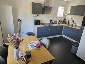 una cucina con tavolo in legno e armadi blu di Ferienwohnung Elya, Ihre Auszeit zwischen Therme, Outlet, Natur a Bad Münstereifel Altre 14 foto