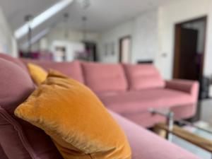 a couch with a pillow in a room with pink couches at Olivia Suite in Bojnice