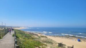 a boardwalk leading to a beach with people walking on it at Granja Beach Front in São Félix da Marinha