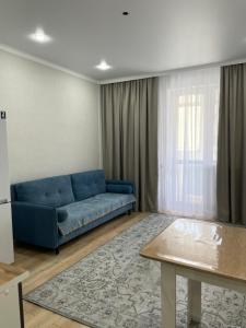 ein Wohnzimmer mit einem blauen Sofa und einem Tisch in der Unterkunft Двухкомнатная квартира in Astana