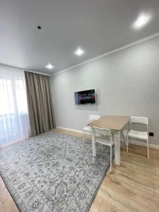ein Esszimmer mit einem Tisch und Stühlen auf einem Teppich in der Unterkunft Двухкомнатная квартира in Astana