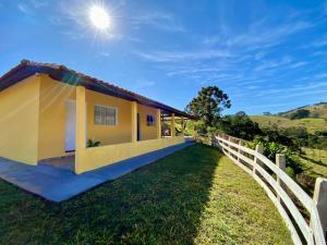 a small yellow house with a white fence at Sitio Boa Esperança II - 20km de Monte Verde in Camanducaia