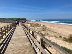 two people walking down a wooden boardwalk to the beach at Casa Sol e Mar - Family stays in Torres Vedras