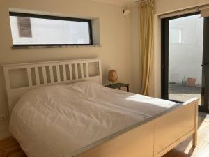 a bedroom with a white bed and a window at Casa Sol e Mar - Family stays in Torres Vedras
