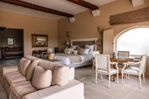 ein Schlafzimmer mit einem Bett, einer Couch und einem Tisch in der Unterkunft Le Phébus & Spa – Relais & Châteaux in Joucas