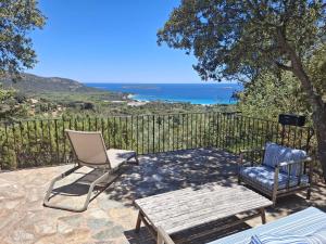 a patio with a bench and a chair and a table at Résidence Belvedere de Palombaggia in Porto-Vecchio