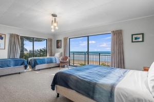 a bedroom with two beds and a balcony with the ocean at Beach Galore - Waihi Beach Holiday Home in Waihi Beach
