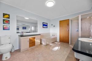 a bathroom with a toilet and a sink and a tub at Beach Galore - Waihi Beach Holiday Home in Waihi Beach +37 photos
