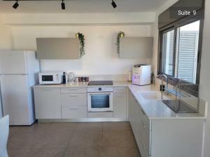 uma cozinha com armários brancos e uma geladeira branca em Magdala Resort 2BR With private pool em Migdal mais 25 fotografias