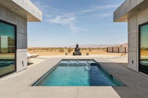 a person sitting next to a swimming pool in a house at Villa Solace by Fieldtrip Modern Desert Oasis w Pool in Joshua Tree