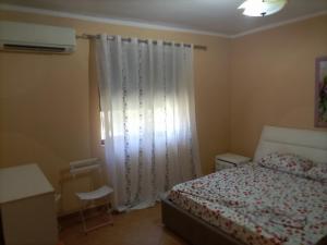 a bedroom with a bed and a window with curtains at Salis Home in Polisi i Vogël