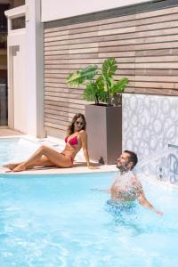 a man and a woman sitting in a swimming pool at Hotel Villa Paola in Rimini