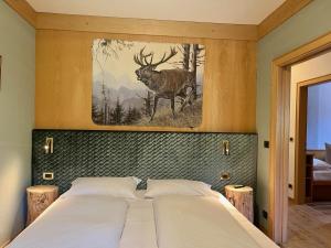 a bedroom with a bed with a picture of a deer at Wellness Residence Panorama - check-in at Olympia Hotel in Arabba