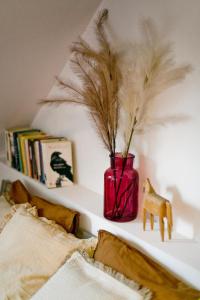 a red vase with feathers on a shelf next to a bed at Stylowy, przestronny apartament 80m2 na zielonej ulicy w centrum in Wrocław +19 photos