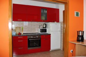 a kitchen with red cabinets and a white refrigerator at Azizam hostel in Split
