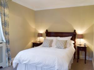 a bedroom with a large white bed with two lamps at The Coach House in Tattingstone