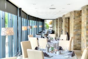 een restaurant met witte tafels, stoelen en ramen bij Hotel De Beurs in Hoofddorp