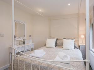 een slaapkamer met een bed met witte kussens en een spiegel bij Hall Cottage in Brampton +10 foto's