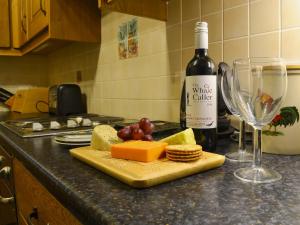 a bottle of wine and a plate of cheese and a glass at Elidir Cottage in Llanwnda