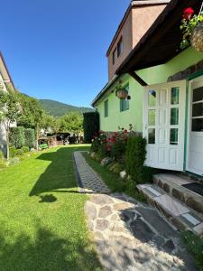 a green house with a white door and a grass yard at Pensiunea Panorama in Băile Tuşnad