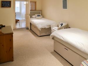 a bedroom with two beds and a chair in it at Tides Reach in Fowey