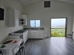 a kitchen with white cabinets and a table in it at WindBlow Villa in Belmont
