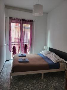 a bedroom with a bed and a window with pink curtains at Casa de Los Amigos in Rapallo