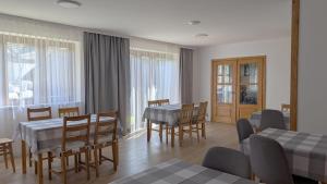 a dining room with tables and chairs and windows at Apartamenty Maciata in Biały Dunajec