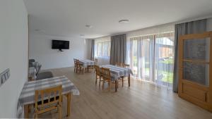 a dining room with tables and chairs and a television at Apartamenty Maciata in Biały Dunajec