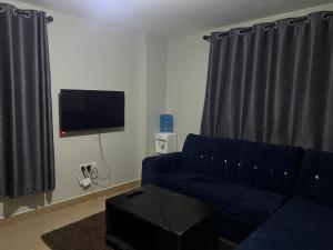 a living room with a blue couch and a tv at Qwetu in Thika