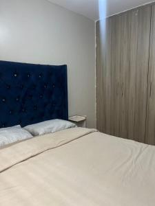 a bedroom with a large bed with a blue headboard at Qwetu in Thika