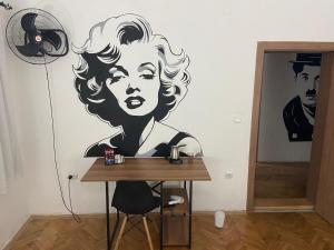 a room with a desk with a painting of a woman on the wall at Stojanovski Apartments in Kumanovo
