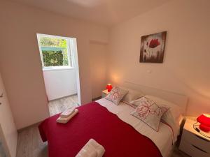 a bedroom with a bed with a red blanket and a window at Apartments Silva in Split +9 photos